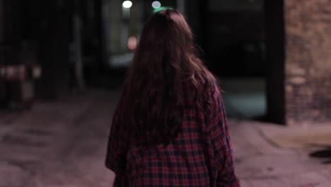 Close-up-Tracking-Shot-Of-A-Woman-Walking-In-A-Checked-Flannel-Along-A-Dark-Sidestreet