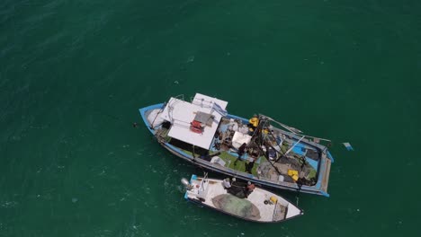 Drone-Tracking-two-fishing-boats-full-of-activity-preparing-to-cast-nets-in-the-bay-close-up,-top-down
