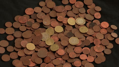 Mehrere-Münzen-Auf-Schwarzem-Tuch-Verteilt,-1-Euro-Münzen-Und-Viele-Andere-20,-10,-5,-2,-1-Cent