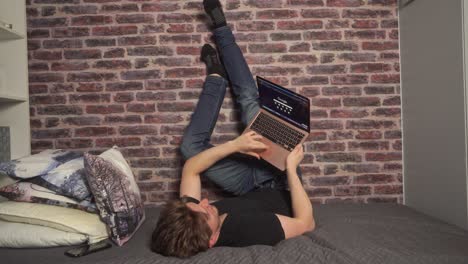 Ein-Student-Stützt-Seine-Füße-Und-Beine-Bei-Der-Arbeit-Am-Computer-Gegen-Eine-Wand