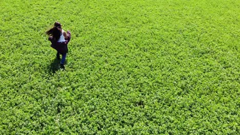 Aerial-Tracking-Shot-Of-A-Young-Girl-Making-Her-Own-Trails-In-A-Stunning-Green-Field