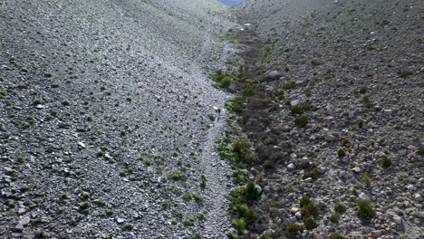 Drone-shot-of-man-walking-through-rocky-valley-in-Pakistan,-Fairy-Meadows