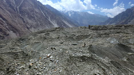 Drone-shot-of-man-standing-on-mountain-peak,-Passu-Cones-Pakistan,-rotating-aerial-shot