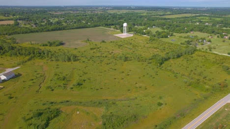 A-water-tower-in-a-green-field-and-a-Drone-Flyover-Aereal-view-Missouri-Suburbs