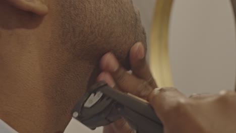 Close-up-of-man-using-trimmer-to-shave-his-face-while-light-flares-in-the-camera-lens