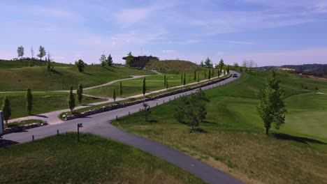 Golfplatz-Und-Straße-Mit-Fahrendem-Lkw-Und-Auto,-Luftdrohnenansicht,-Sonniger-Tag,-Grünes-Gras,-Kacov-In-Der-Tschechischen-Republik