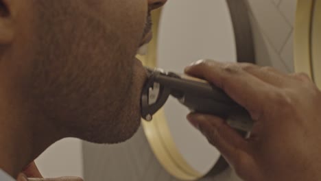 Man-in-bathroom-shaving-his-mustache-and-beard-with-a-electronic-trimmer