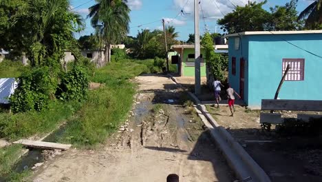 Drone-shot-of-kids-playing-in-a-rural-street-of-Higuey,-La-Altagracia-province