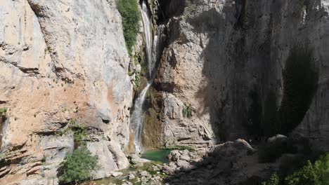Aufsteigender-Schuss-Auf-Den-Wasserfall-Der-Reue-In-Den-Bergen,-Während-Wasser-Aus-Der-Höhe-Fällt-Und-Einen-Teich-In-Stein-Gemeißelt,-Der-Die-Umgebung-Bildet