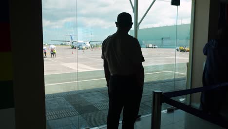 A-Silhouette-Pilot-Looking-at-an-Aircraft-From-Inside-the-Airport-4K