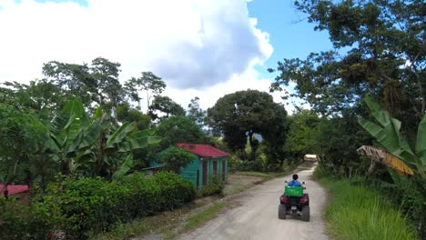 A-woman-and-a-boy-driving-in-a-rural-street-of-the-caribbean-in-a-community-called-San-Jose-de-Ocoa,-at-the-Dominican-Republic-,-the-road-is-bumpy-and-the-day-is-sunny