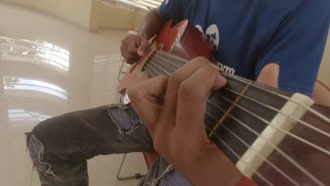 FPV-Shot-of-an-acoustic-guitar-being-played-by-a-boy,-fingers-in-shot