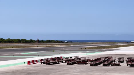 Kleines-Flugzeug,-Das-Auf-Dem-Flughafen-Der-Baleareninsel-Ibiza-Landet,-Und-Gepäckwagen,-Die-Auf-Dem-Flugplatz-Geparkt-Sind
