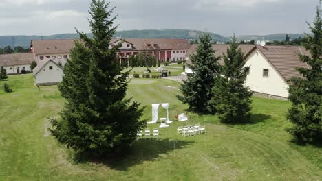 White-wedding-altar-and-chairs-at-estate-wedding,-aerial-wide-shot