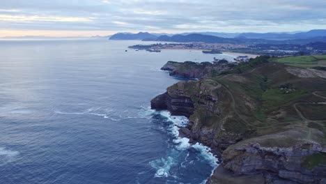 Drone-capture-the-green-island-of-Isla,-Cantabria-from-the-great-height-on-cloudy-day