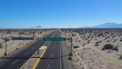 View-of-a-drone-flying-back-over-a-sign-on-a-highway-that-says-"Bienvenidos-a-San-Felipe
