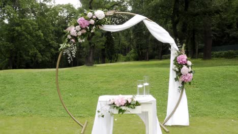 Wedding-altar,-circular-arch-and-chairs-in-park,-backwards-dolly-shot
