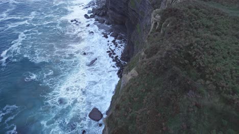 Drone-Captura-El-Borde-De-La-Colina-En-Isla-Y-También-El-Mar-Cantábrico-Azul-Golpeando-Las-Rocas-Desde-Una-Gran-Altura