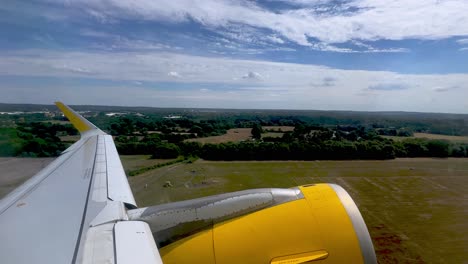 Passenger-point-of-view-of-yellow-jet-commercial-airplane-wing-and-engine-during-takeoff-from-London-Gatwick-airport-in-UK