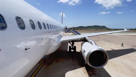 Tilt-up-view-from-front-door-of-fuselage-wing-and-engine-of-airplane-parked-at-Ibiza-Balearic-island-airport-with-stairs-attached-on-sunny-day