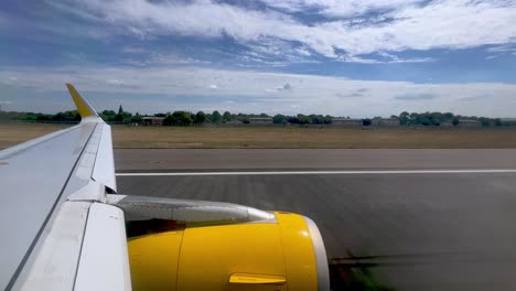 Passenger-point-of-view-of-yellow-jet-commercial-airplane-wing-and-engine-during-takeoff-from-London-Gatwick-British-airport-in-United-Kingdom