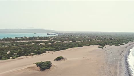 Aerial-view-overlooking-the-coast-of-Las-Dunas-De-Bani-in-Dominican-Republic---pan,-drone-shot