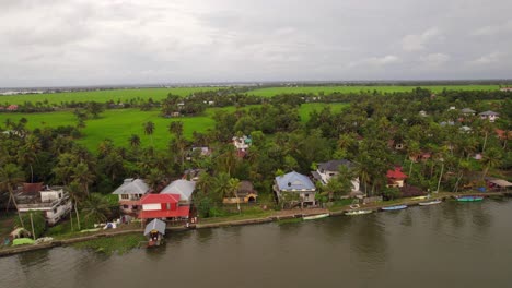 Aerial-high-rise-revealing-traditional-houses-in-marshes-of-Kerala,-south-India