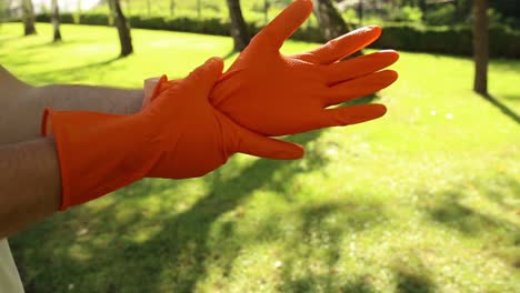 Nahaufnahme-Der-Hände-Des-Mannes,-Die-Orangefarbene-Gummihandschuhe-Anziehen