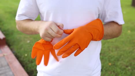 Der-Mann-Legt-Orangefarbene-Schutzhandschuhe-An-Und-Zieht-Sie-Aus,-Um-Mit-Der-Reinigung-Zu-Beginnen