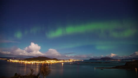 Time-lapse-of-northern-lights-shining-over-the-nightly-illuminated-city-of-Aalesund,-Norway
