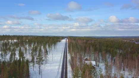 Drone-footage-rising-above-icy-road-and-endless-forest-view-in-Finland