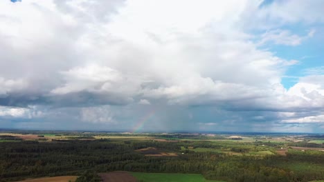 The-Rainbow-Over-the-Crop-Field-With-Blooming-Wheat,-During-Spring,-Aerial-View-Under-Heavy-Clouds-Before-Thunderstorm-6