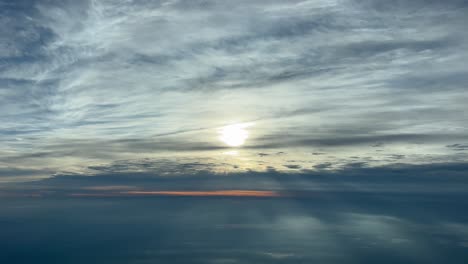 Fantastische-Luftaufnahme-Aus-Einem-Jet-Cockpit-Eines-Wunderschönen-Himmels-Mit-Der-Sonnenscheibe,-Die-Nach-Einigen-Stratuswolken-Während-Des-Sonnenuntergangs-Verhüllt-Ist
