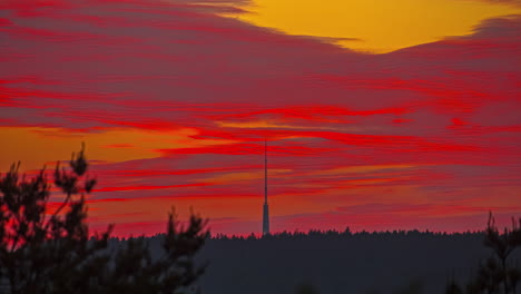 Time-lapse-of-a-tall-radio-tower-in-the-background-of-the-video-under-an-incredible-reddish-sunset-with-clouds