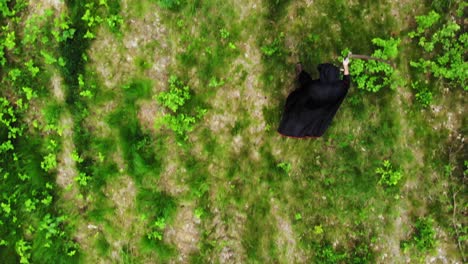 Overhead-View-Of-A-Creepy-Angel-Of-Death-With-Scythe-Walking-In-Verdant-Forest