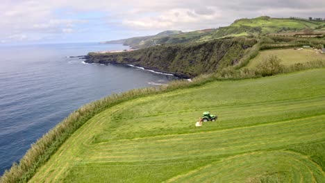 Tractor-cutting-grass-in-coastal-countryside,-Azores,-aerial-view
