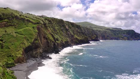 Waves-crushing-on-rugged-grassy-coastline-cliffs,-Azores,-aerial-view