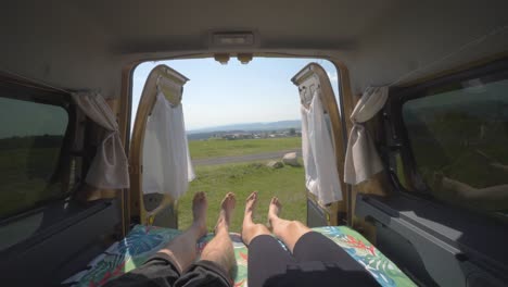 Nomadic-couple-lying-down-moving-their-feet-in-unison-inside-a-camper-van