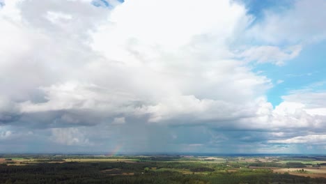 The-Rainbow-Over-the-Crop-Field-With-Blooming-Wheat,-During-Spring,-Aerial-View-Under-Heavy-Clouds-Before-Thunderstorm-1