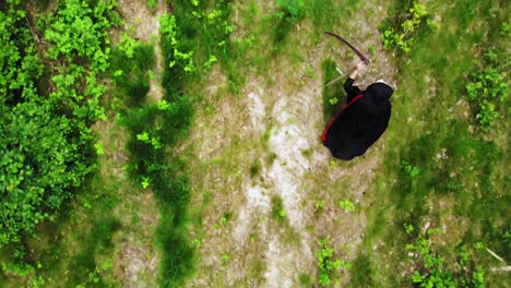 Overhead-View-Of-A-Grim-Reaper-With-Scythe-Walking-In-The-Midst-Of-Forest