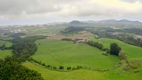 Green-countryside-landscape-in-Azores-covered-in-mist-clouds,-aerial