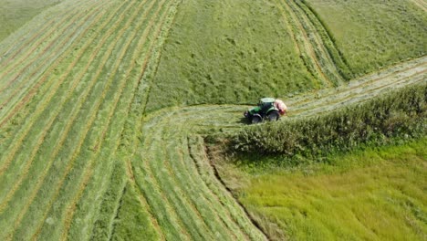 Tractor-cutting-grass-of-steep-green-hill-field-in-Azores,-aerial-view
