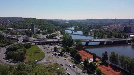 Aerial-drone-view-of-traffic-on-road-junction-or-crossroad,-Prague,-Czech-Republic,-Vltava-river-and-city-in-background