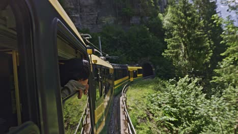 Paseo-Panorámico-En-Tren-En-El-Valle-De-La-Ventana-De-Montaña-De-Los-Alpes-Con-Un-Hombre-Mirando-Desde-La-Ventana,-Lauterbrunnen-Suiza-2