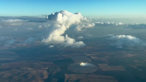 Nice-view-from-a-jet-cockpit-of-a-tiny-cumulus-ahead-overflying-a-rounded-solar-farm-in-Andalucia,-Spain