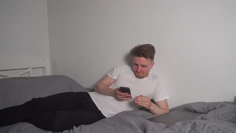 A-young-man-lays-down-on-his-bed-and-replies-to-responses-from-a-dating-app