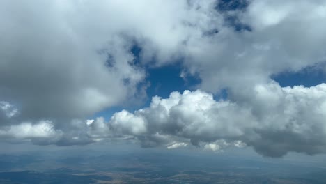 Aerial-view-from-a-jet-cockpit-while-flying-between-some-tiny-cumulus-clouds-in-a-deep-blue-sky