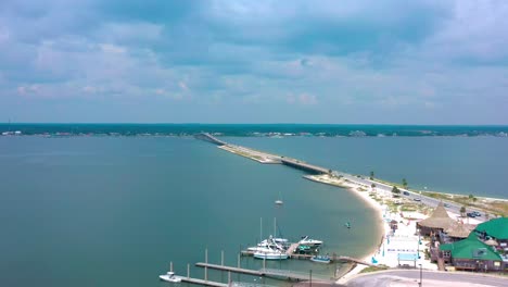 Aerial-view-flying-over-Navarre-Beach-FL-looking-at-the-bridge-going-over-the-bay