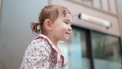 Profile-of-young-happy-toddler-girl-with-pigtails-looking-up-and-smiling---shallow-focus
