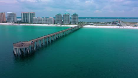 Aerial-drone-panning-left-view-of-the-Navarre-Beach-Florida-Pier-with-some-dark-clouds-in-the-background